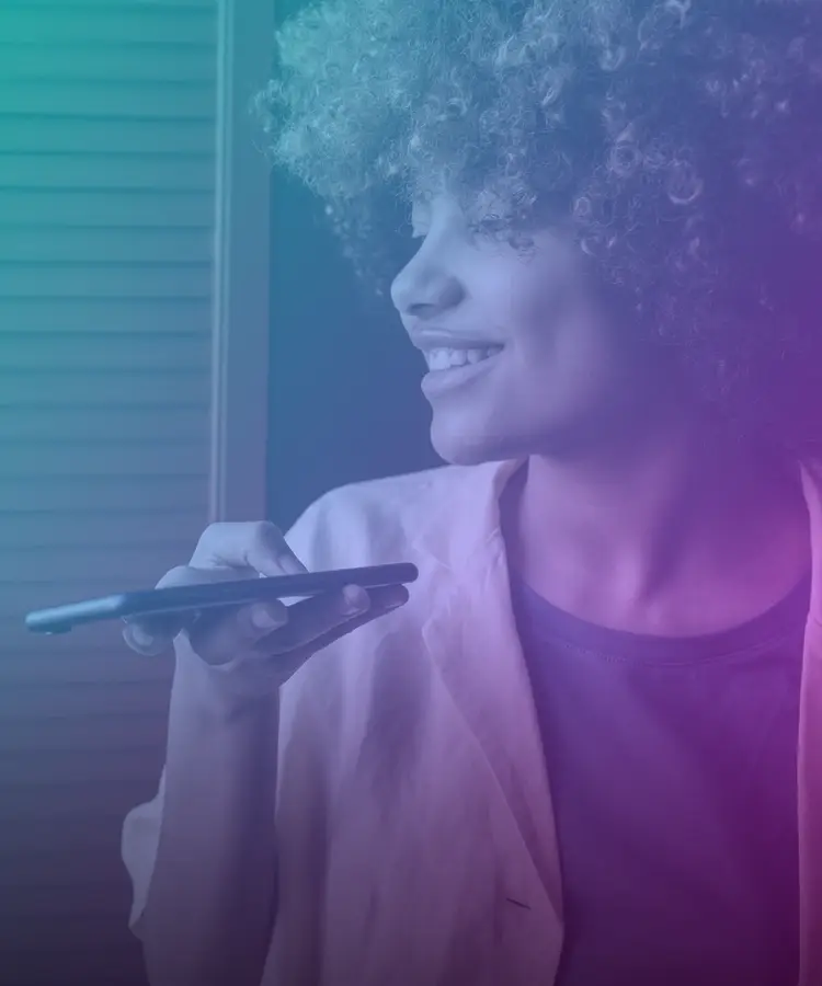Mujer sonriente que le hace una pregunta a un asistente de voz en su teléfono